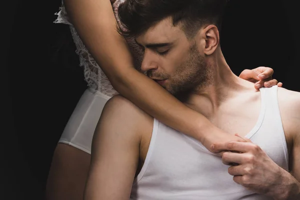 Partial view of young woman in white lingerie near boyfriend kissing her hand isolated on black — Stock Photo