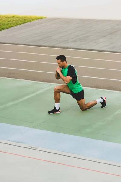 Mixed race sportsman in sportswear stretching at stadium — Stock Photo