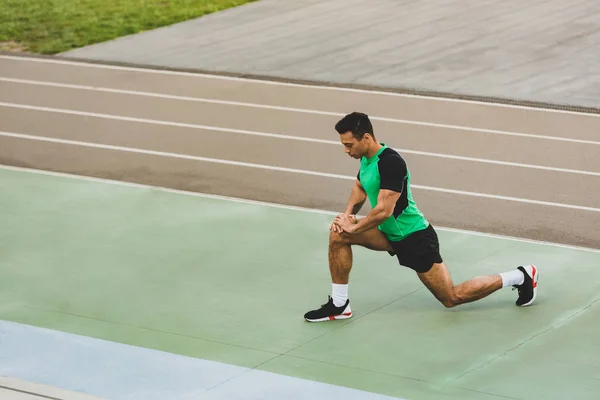 Змішана гонка спортсмен в спортивному одязі, що тягнеться на стадіоні — стокове фото