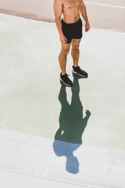Обрізаний вид на спортсмена без сорочки, що стоїть на стадіоні — стокове фото