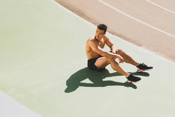 Stanco bello sportivo di razza mista seduto allo stadio — Foto stock