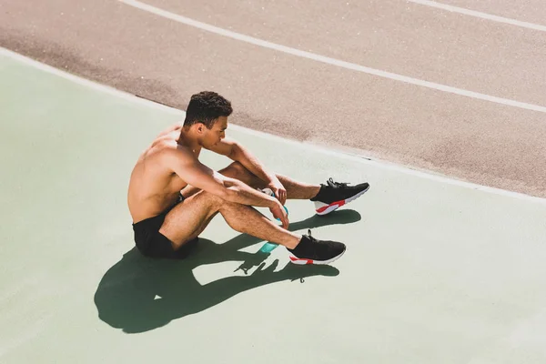 Втомилися від гарного змішаної раси спортсмен сидячи на стадіоні — стокове фото