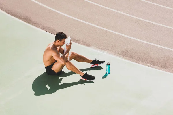 Змішана гонка спортсмен сидить на стадіоні і протирає обличчя рушником — стокове фото