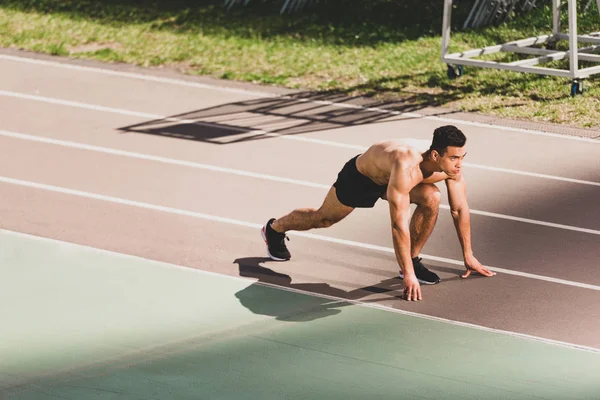 Mixed race sportsman preparing to run at stadium — Stock Photo