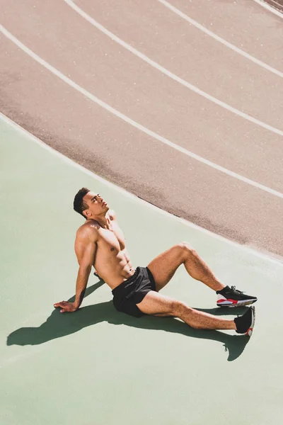 Hemdloser Mixed-Race-Sportler sitzt mit geschlossenen Augen im Stadion — Stockfoto