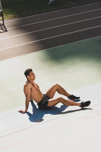 Втомлений красивий змішаний спортсмен, що сидить на стадіоні — стокове фото