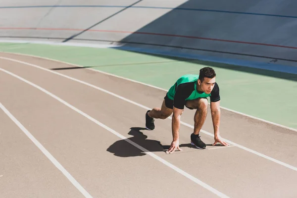 Спортсмен смешанной гонки готовится к бегу на стадионе — стоковое фото
