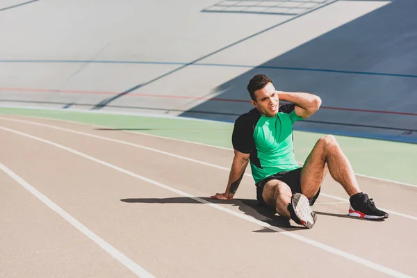 Müder Sportler in Sportbekleidung sitzt im Stadion — Stockfoto