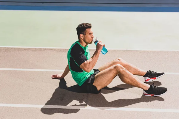 Mixed Race Sportler sitzt im Stadion und trinkt Wasser — Stockfoto