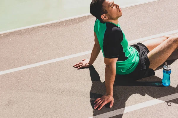 Cansado guapo mezclado carrera deportista sentado en el estadio - foto de stock