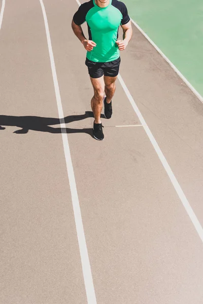 Обрізаний вид спортсмена в спортивному одязі, що біжить на стадіоні — стокове фото