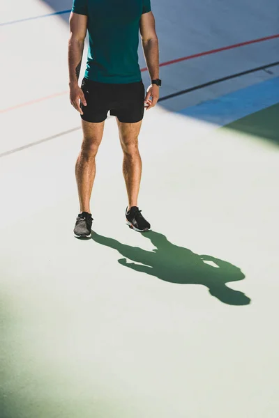 Cropped view of sportsman standing in light place at stadium — Stock Photo