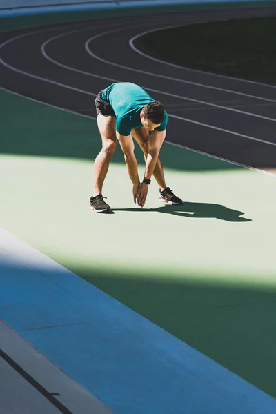 Desportista de raça mista aquecendo no estádio, de pé no chão verde à luz do sol — Fotografia de Stock