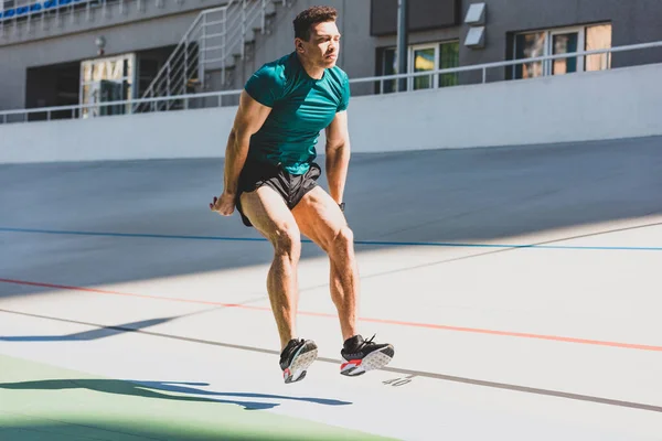 Mixed race sportsman doing long jump at stadium in sunlight — Stock Photo