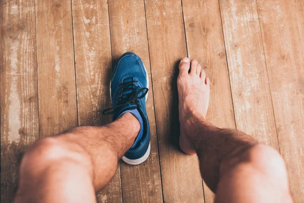 Cropped shot of sportsman sitting in one sneaker and with one bare foot — Stock Photo