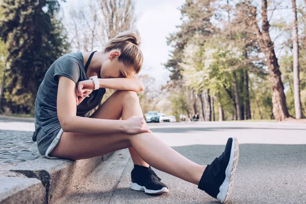 Sportive blessée pleurant alors qu'elle était assise à la frontière du trottoir et souffrant de douleur — Photo de stock