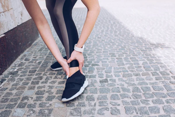 Teilbild einer Sportlerin, die auf Gehweg steht und verletztes Bein berührt — Stockfoto