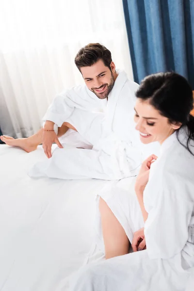 Messa a fuoco selettiva di uomo allegro guardando donna felice in camera d'albergo — Foto stock