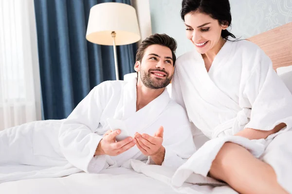 Foco seletivo do homem alegre olhando para a mulher bonita no quarto de hotel — Fotografia de Stock