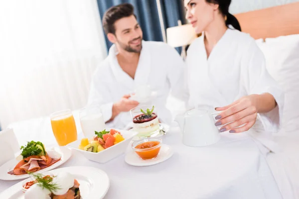 Enfoque selectivo de pareja feliz cerca de la mesa con desayuno - foto de stock