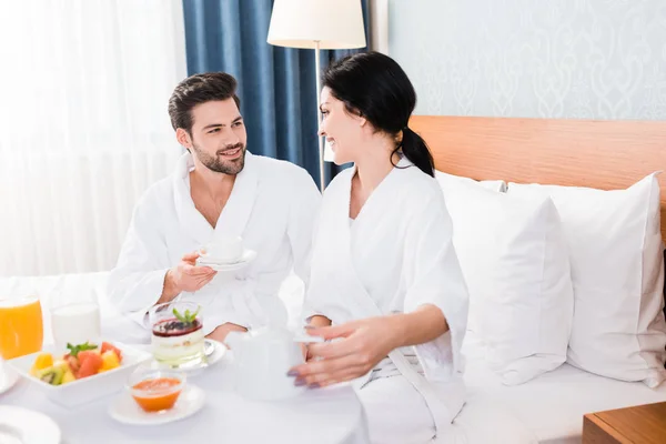 Foco seletivo de homem feliz e mulher perto da mesa com café da manhã — Fotografia de Stock