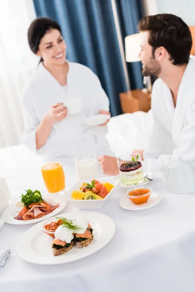 Enfoque selectivo de delicioso desayuno cerca de feliz hombre y mujer - foto de stock