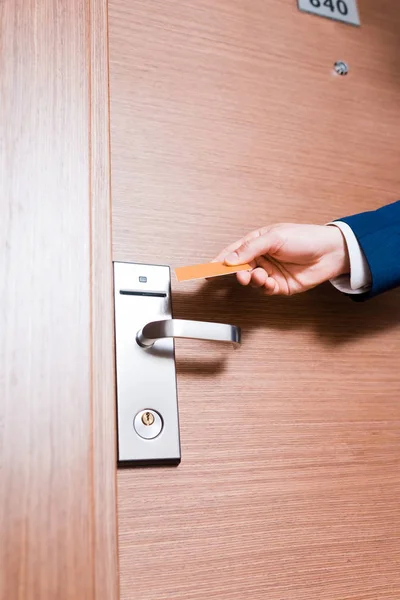 Vista recortada del hombre de negocios con tarjeta de hotel cerca de la puerta - foto de stock