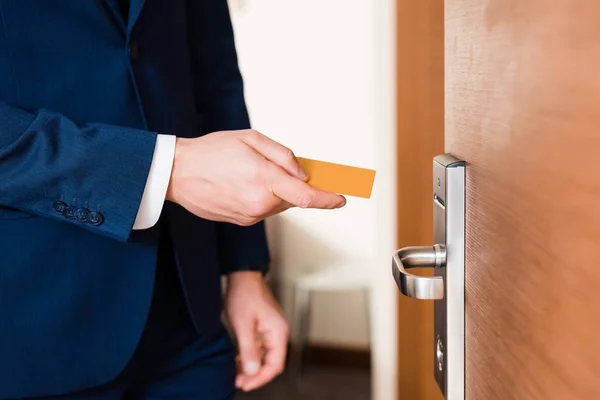 Vista recortada del hombre de negocios que sostiene la tarjeta del hotel mientras está de pie cerca de la puerta - foto de stock