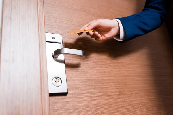 Vista recortada del hombre sosteniendo la tarjeta del hotel mientras está de pie cerca de la puerta - foto de stock