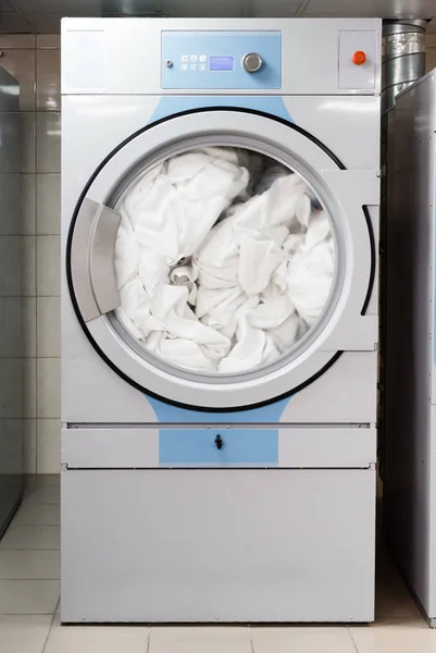 White bed sheets in electric washing machine in laundry in hotel — Stock Photo