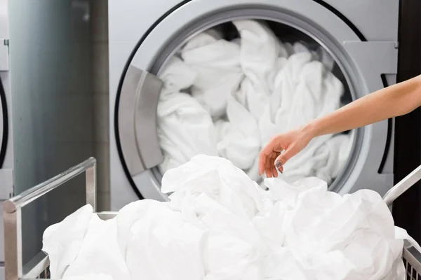 Cropped view of housemaid near white bed sheets in laundry — Stock Photo