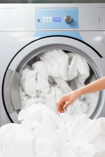 Cropped view of maid near white bed sheets in laundry — Stock Photo