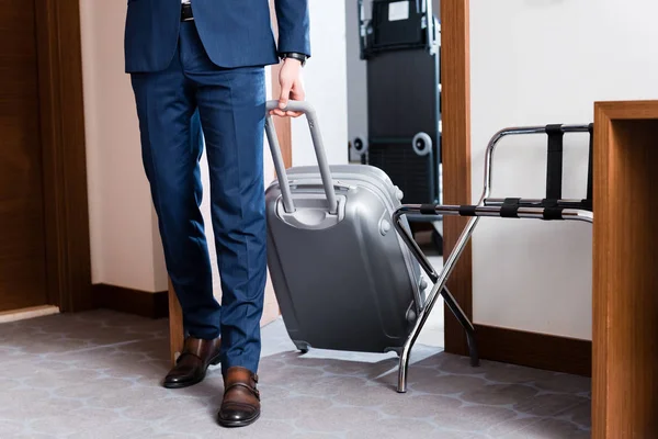 Cropped view of man in formal wear entering hotel room with luggage — Stock Photo