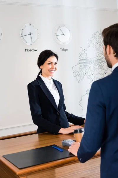 Ausgeschnittene Ansicht eines Mannes, der in der Nähe der glücklichen Rezeptionistin im Hotel steht — Stockfoto