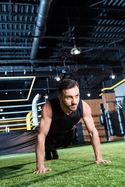 Handsome bearded man doing plank exercise on green grass — Stock Photo