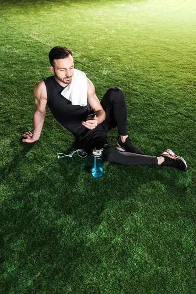 Overhead view of handsome man using smartphone while sitting on grass — Stock Photo