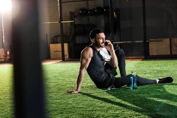 Foyer sélectif de l'homme heureux parlant sur smartphone tout en étant assis sur l'herbe — Photo de stock