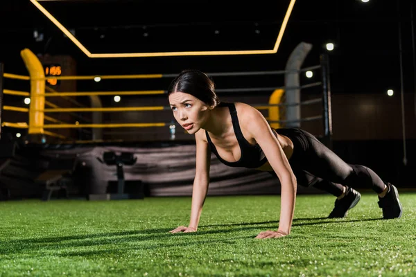 Attractive and athletic woman doing press ups on green grass — Stock Photo