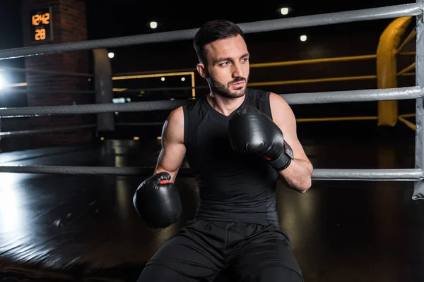 Handsome bearded man in black boxing gloves in gym — Stock Photo