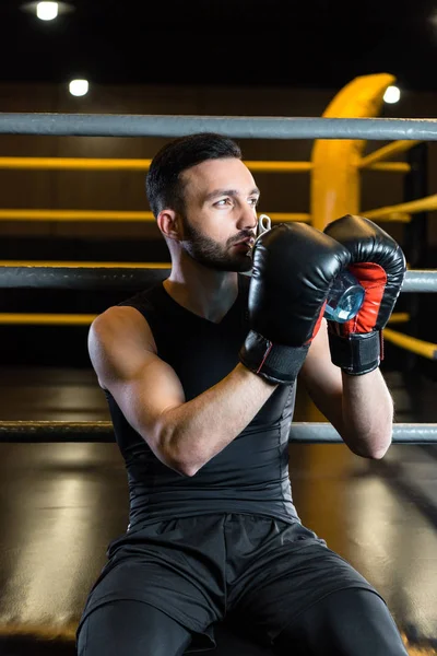 Handsome man in boxing gloves drinking water in sports center — Stock Photo