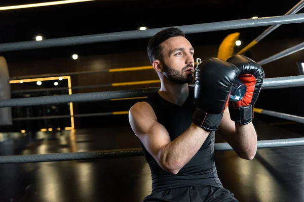 Athletic man in boxing gloves drinking water in sports center — Stock Photo