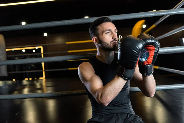 Sportlicher Mann in Boxhandschuhen trinkt Wasser im Sportzentrum — Stockfoto