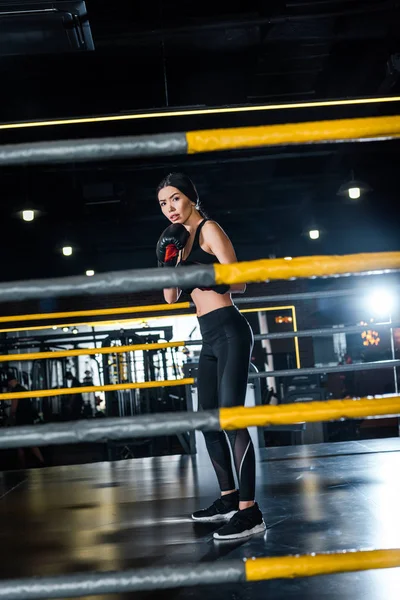 Selective focus of attractive woman boxing while standing in boxing gloves in gym — Stock Photo