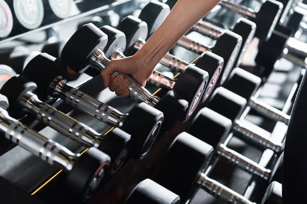 Cropped view of athletic young woman taking heavy dumbbell in gym — Stock Photo