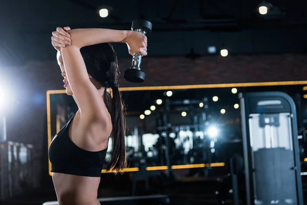 Jeune femme athlétique travaillant avec haltère dans la salle de gym — Photo de stock