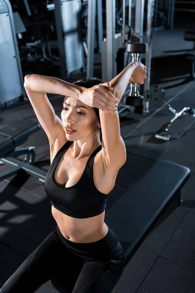 Overhead view of young athletic woman working out with dumbbell in gym — Stock Photo