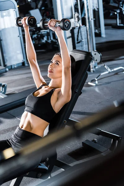 Selective focus of young athletic woman working out with dumbbells — Stock Photo
