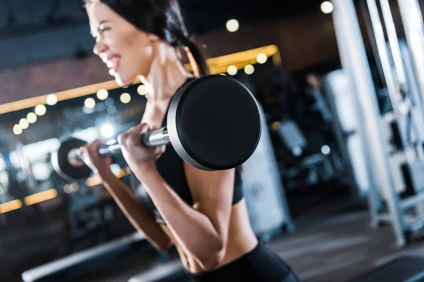 Foyer sélectif de la jeune femme travaillant avec haltère lourde dans la salle de gym — Photo de stock