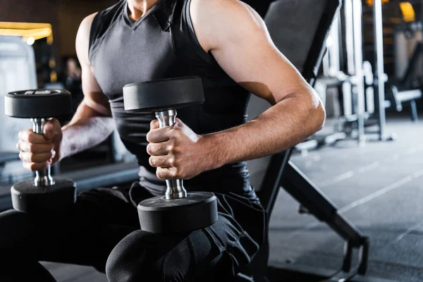 Vista recortada del hombre atlético haciendo ejercicio con pesas en el gimnasio - foto de stock