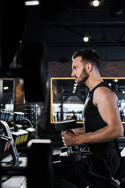 Bell'uomo atletico che si allena con i manubri in palestra — Foto stock